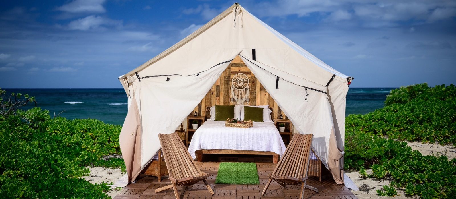 Luxury glamping tent set up on a beach with wooden flooring, cozy bed, and chairs showcasing stylish tent flooring ideas.