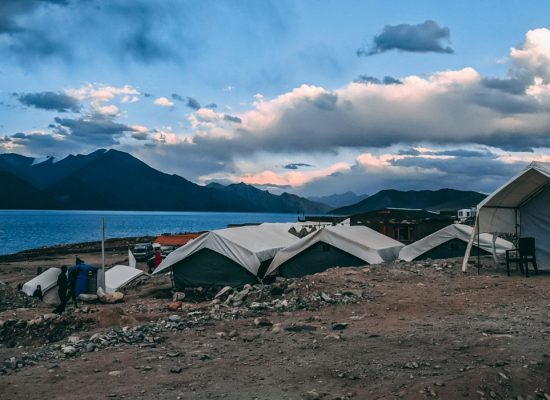 Disaster relief tents set up near a lake and mountains, providing emergency shelter for people in need.