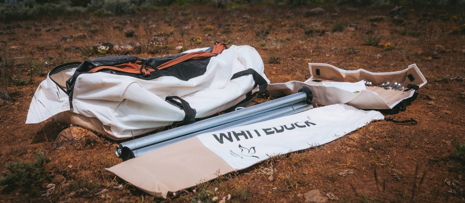 Tent poles and camping hardware from WhiteDuck Outdoors laid out on the ground before setup.