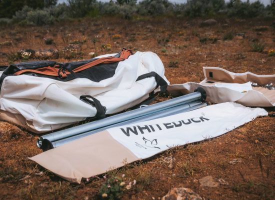 Tent poles and camping hardware from WhiteDuck Outdoors laid out on the ground before setup.