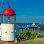 Scenic view of a small lighthouse and pier along the waterfront in Titusville, Florida, with clear blue skies and calm waters.