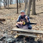 Person building a DIY wooden bench in a forest using hand tools and wearing a canvas apron.