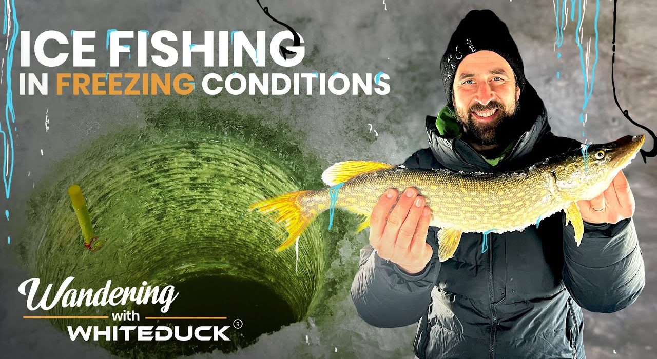 Man holding a fish caught while ice fishing in freezing conditions, standing near an ice hole with the text “Ice Fishing in Freezing Conditions – Wandering with WhiteDuck.”