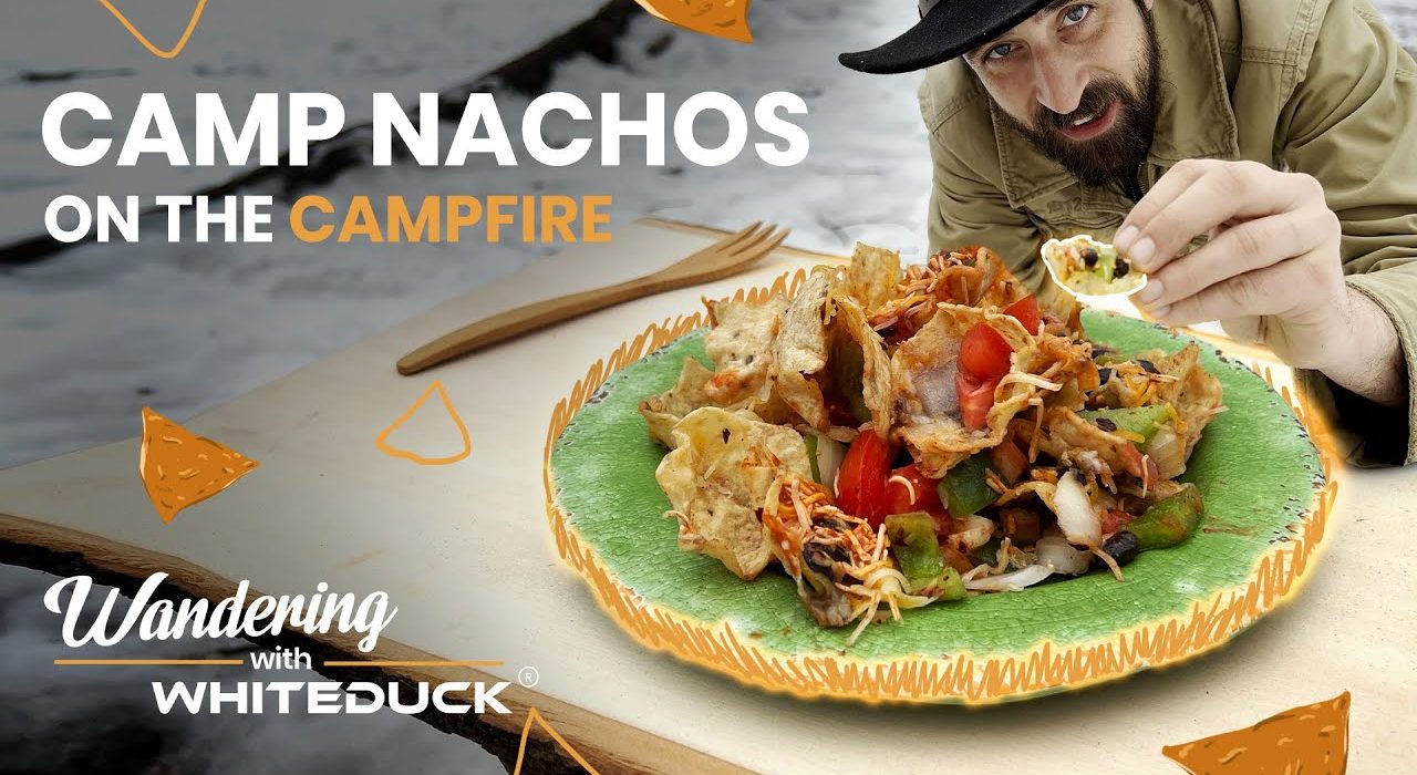 Jack Steward enjoying cheesy campfire nachos cooked outdoors, part of the Wandering with WhiteDuck series on outdoor cooking.