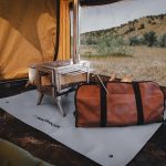 Tent stove set up inside a canvas tent with a fireproof mat and carry bag, providing safe and efficient heating for camping