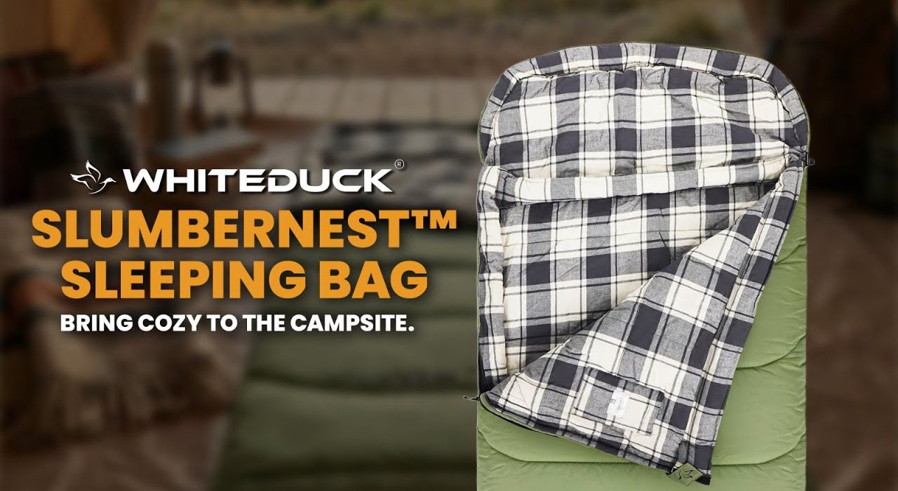 WhiteDuck SlumberNest sleeping bag displayed at a campsite, featuring a cozy plaid interior and insulated design for comfortable outdoor camping sleep.
