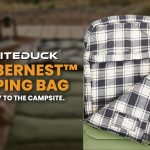 WhiteDuck SlumberNest sleeping bag displayed at a campsite, featuring a cozy plaid interior and insulated design for comfortable outdoor camping sleep.