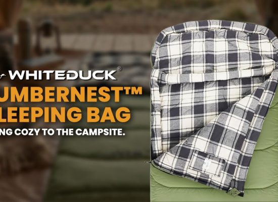 WhiteDuck SlumberNest sleeping bag displayed at a campsite, featuring a cozy plaid interior and insulated design for comfortable outdoor camping sleep.
