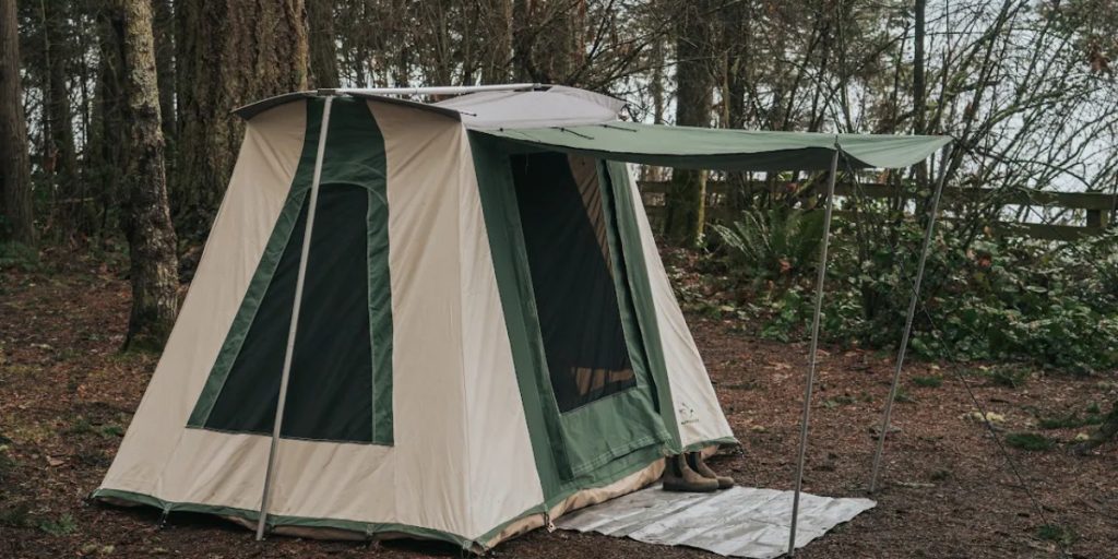 White Duck Outdoors canvas cabin tent set up in a wooded campsite.