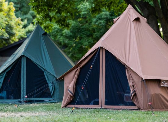 Canvas tents secured with properly angled guylines, demonstrating improved tent stability and wind resistance in outdoor camping conditions.