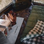 Sleeping bag laid out inside a canvas camping tent with a wood stove and camping gear for a warm and comfortable outdoor setup