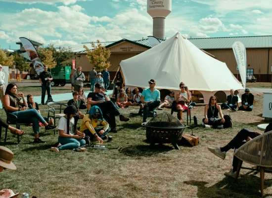 People sitting near tents at an outdoor camping basecamp during a festival