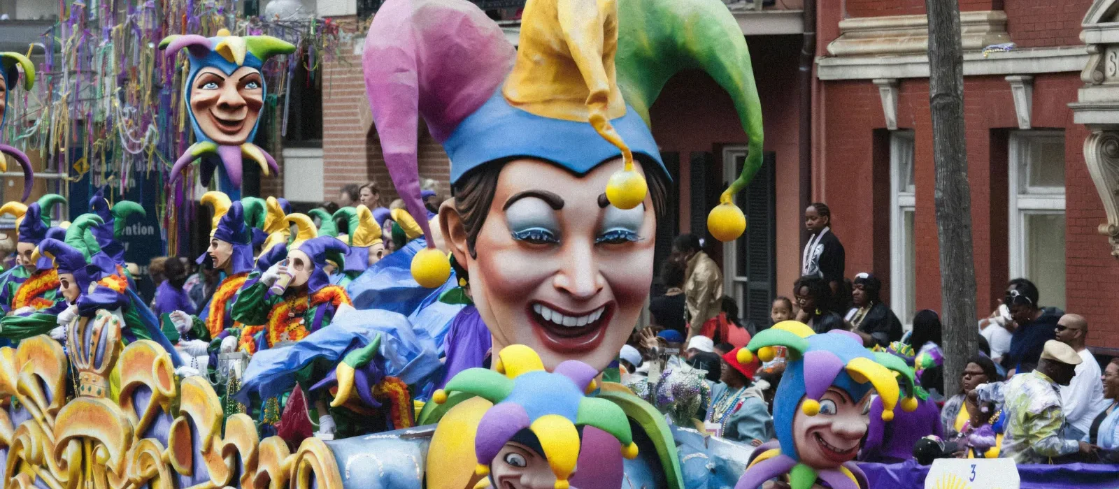 Mardi Gras parade float with colorful jester masks and crowd in New Orleans