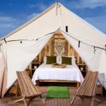 Stylish glamping tent at a beach campsite with ocean view and cozy bed setup