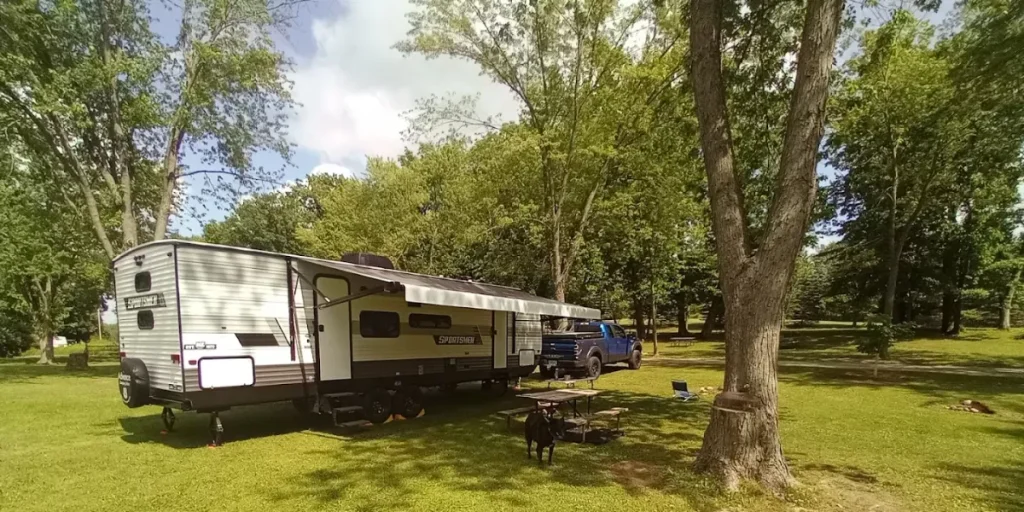 RV setup at Benson Lake campsite with picnic table, truck, and shaded grassy area surrounded by tall trees.
Credit: Benson Lake campsite GMB