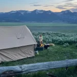 Multi-generational family camping with canvas tent and campfire in scenic mountain landscape