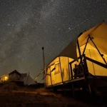 Luxury canvas glamping tent under a starry night sky in Utah desert campsite.