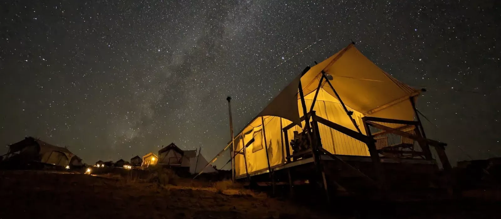 Luxury canvas glamping tent under a starry night sky in Utah desert campsite.