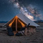 Luxury glamping tent in a desert landscape under the Milky Way galaxy with telescope and outdoor chairs at night.