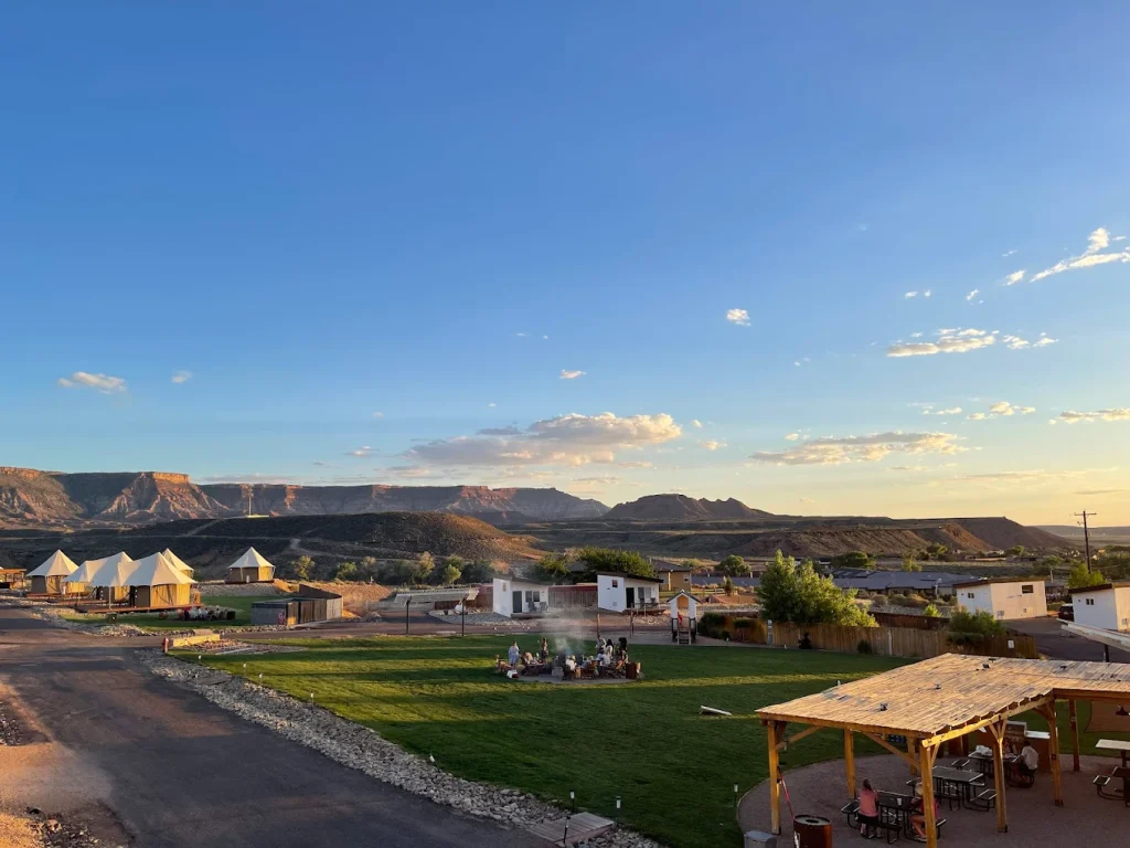An elevated wide shot of Zion Wildflower Resort featuring a variety of glamping accommodations, including white bell tents and modern white bungalows.