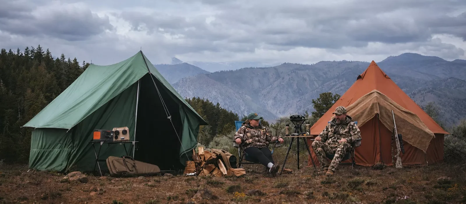Hunters relaxing at a well-organized backcountry hunting camp with canvas tents, secured gear, and a mountain landscape in bear country.