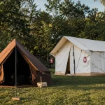 Canvas bell tent and white wall tent at a scenic outdoor camping campsite