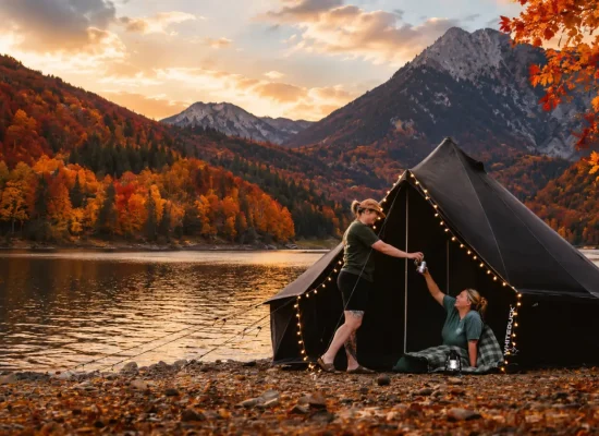 Fall foliage glamping with a canvas tent beside a mountain lake surrounded by colorful autumn trees