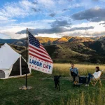 Labor Day camping trip with a white bell tent and American flag in a mountain campsite