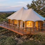 Luxury glamping tent on an elevated wooden deck overlooking the Texas Hill Country at sunset