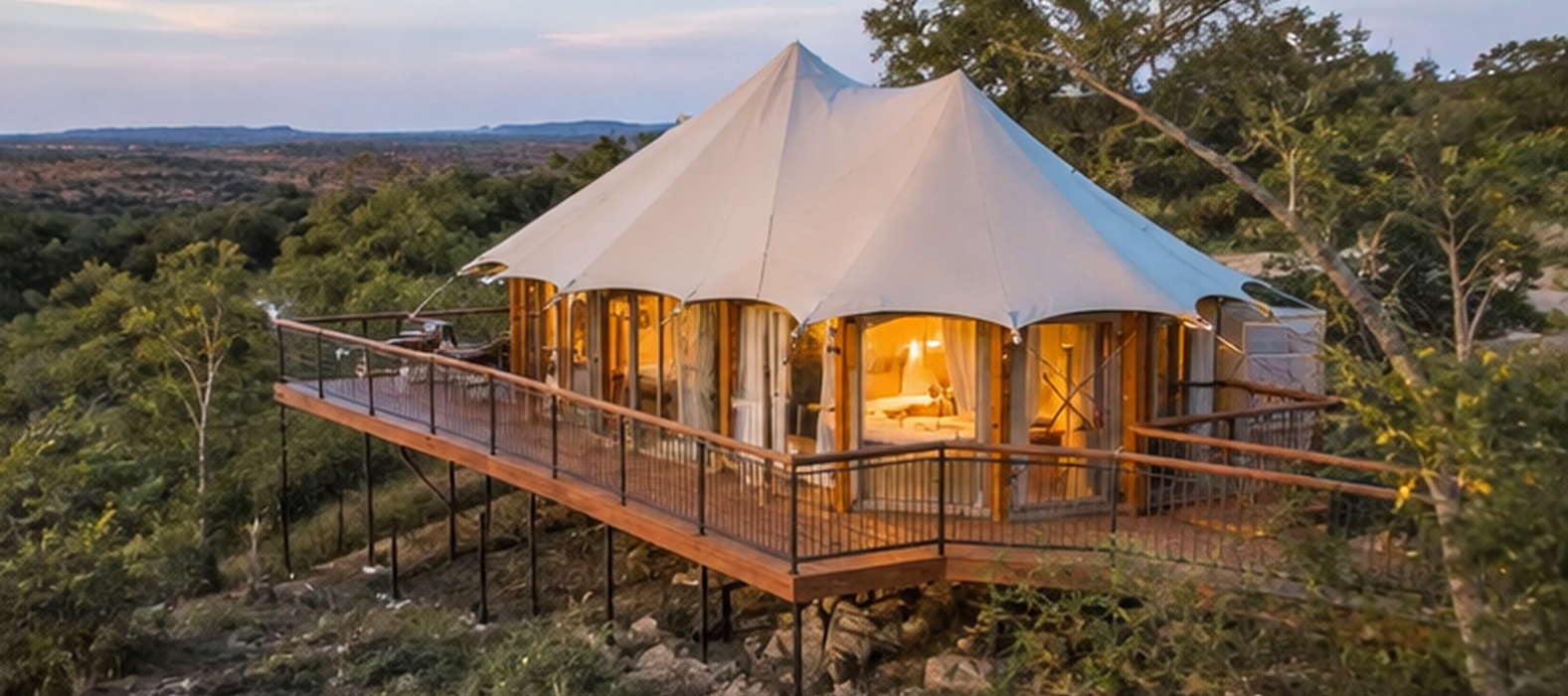 Luxury glamping tent on an elevated wooden deck overlooking the Texas Hill Country at sunset